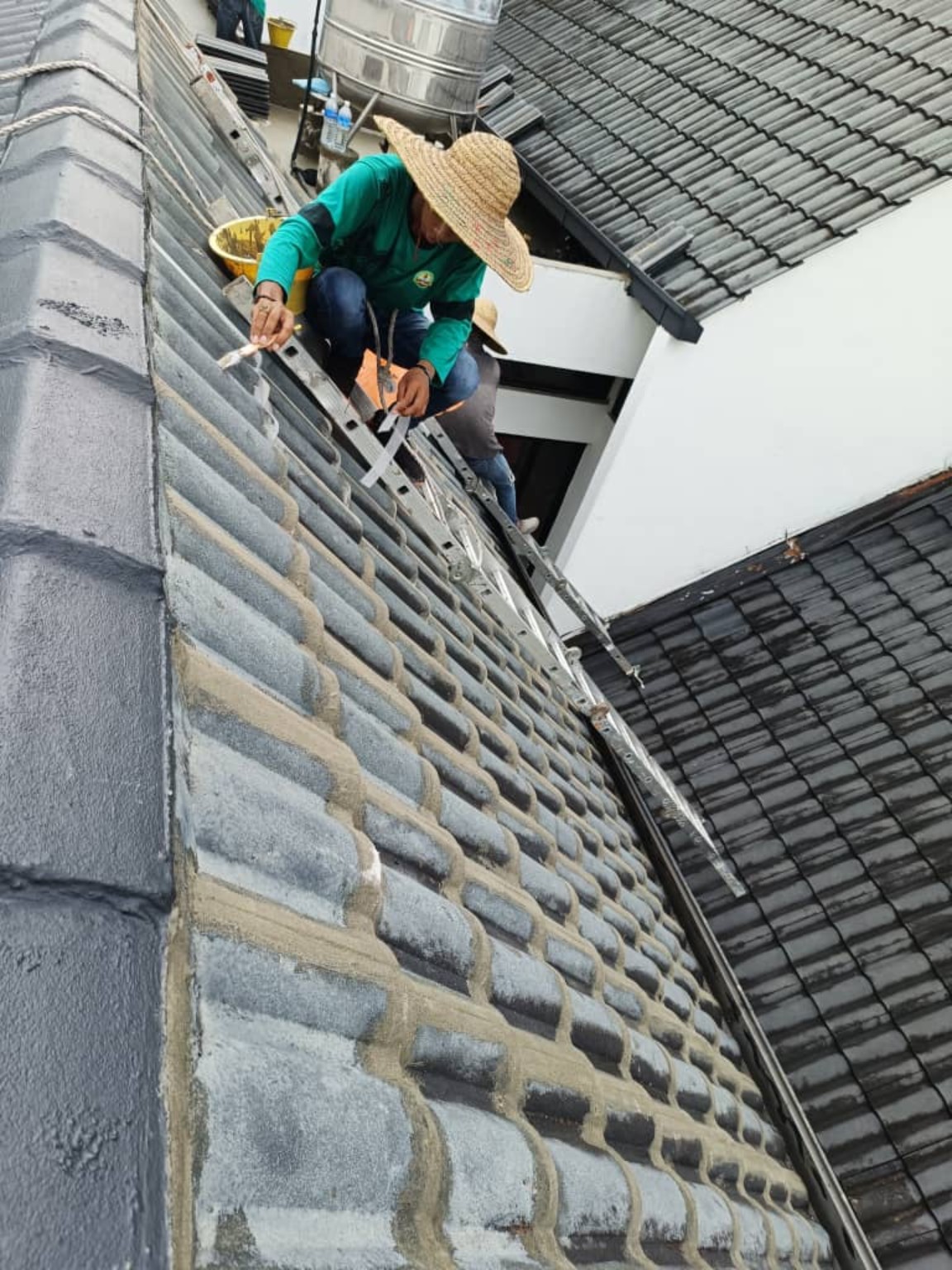 Worker applying waterproofing treatment to roof tile detail